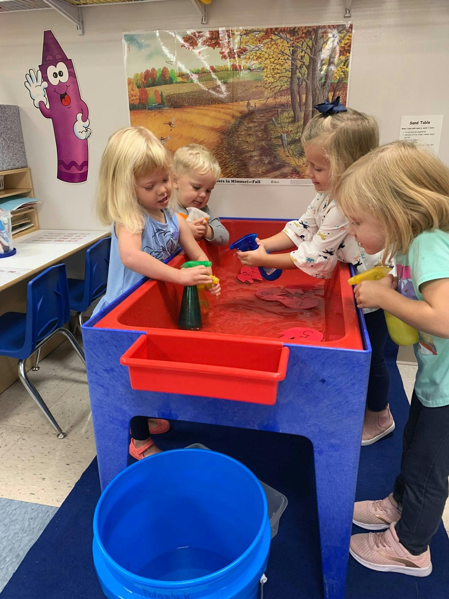 Four children playing at a water table