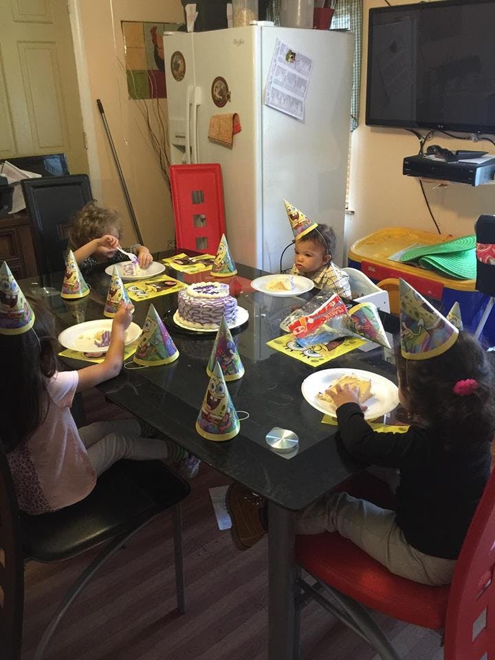 Children wearing party hats eating cake at a table