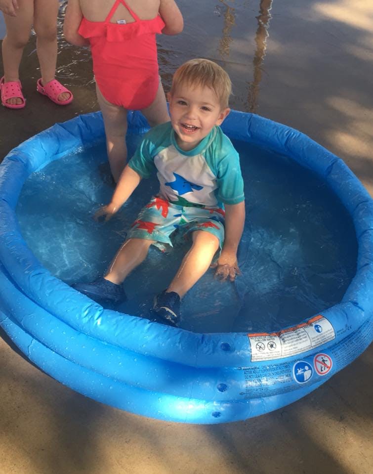 Child sitting in a blue inflatable pool