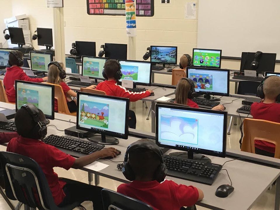 Children in a classroom using computers with headphones