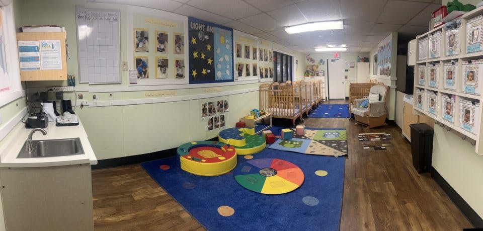 Classroom with cribs, play mats, sink, and bulletin boards
