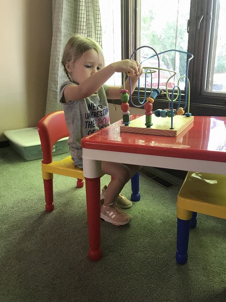 Child playing with a bead maze toy at a table