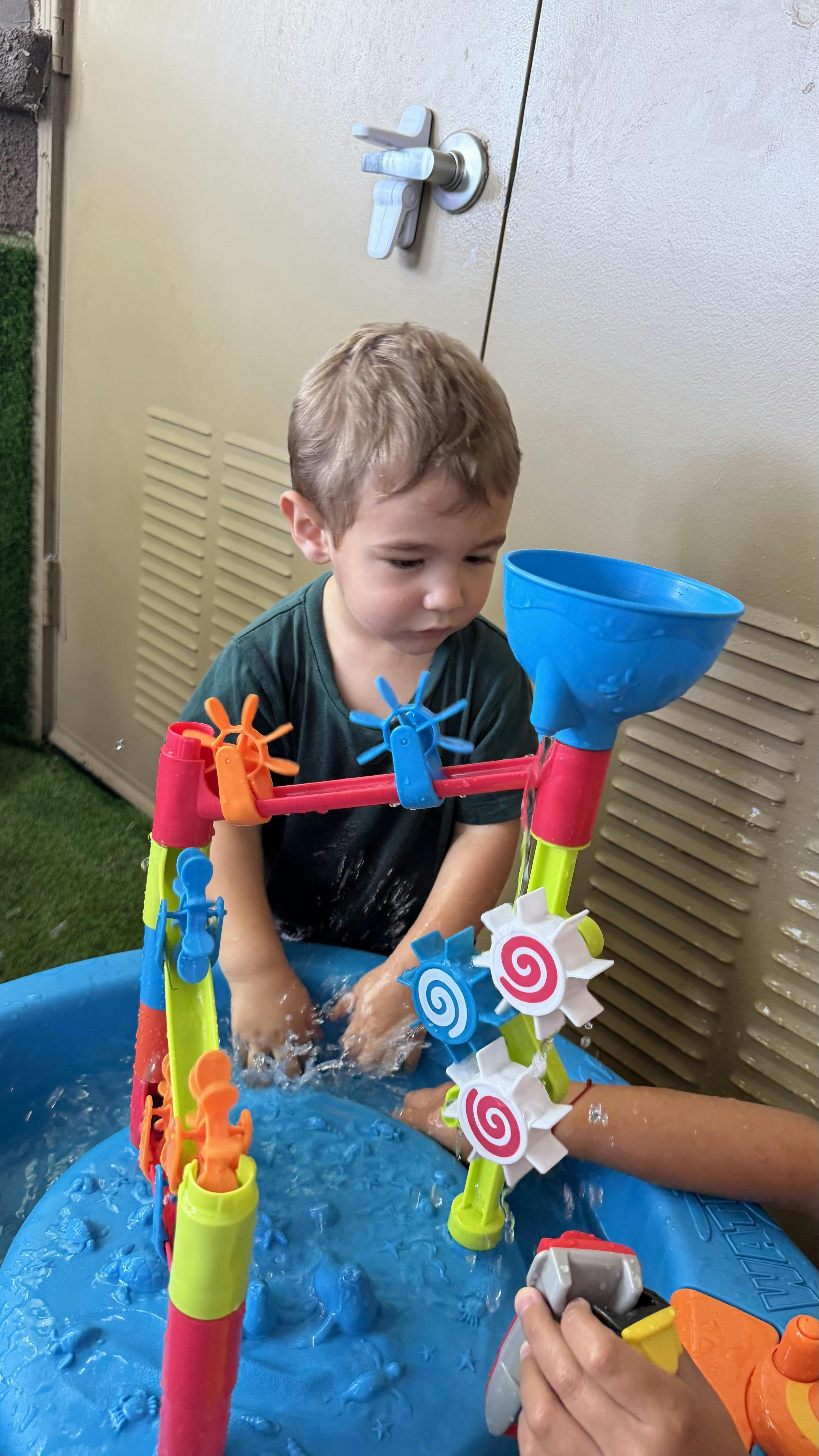 Child playing with a water table featuring spinning wheels