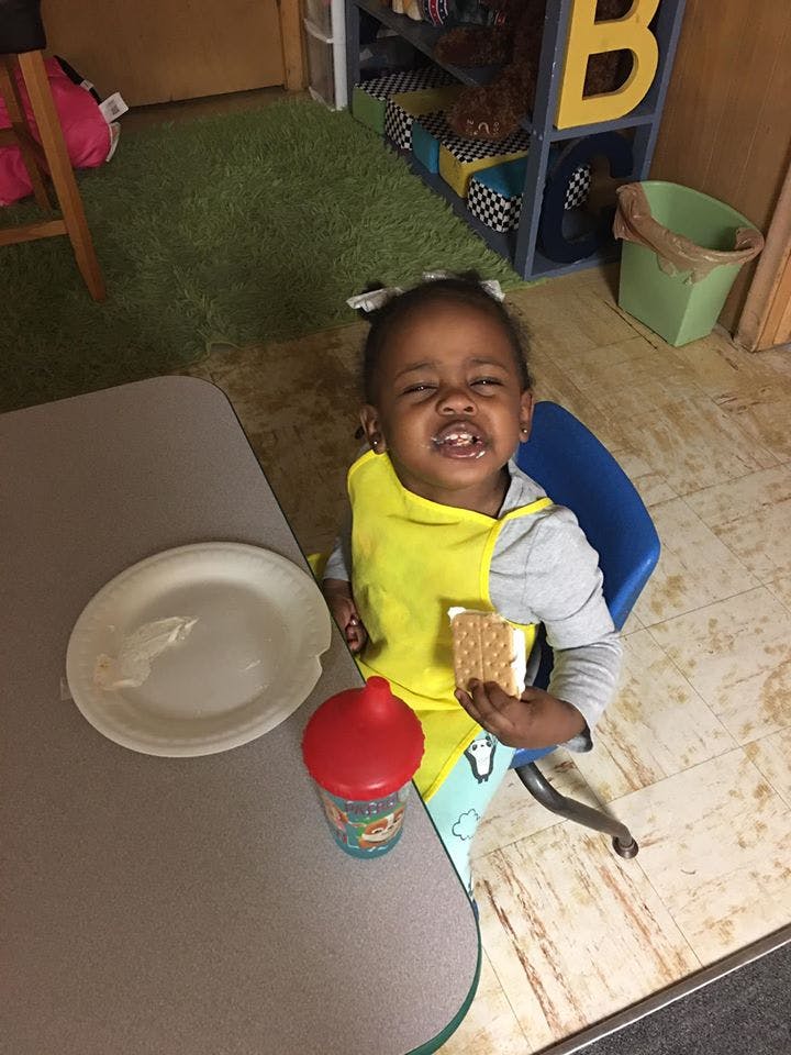 Child in a yellow bib holding a snack