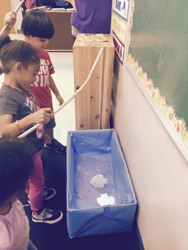 Children playing a fishing game in a classroom