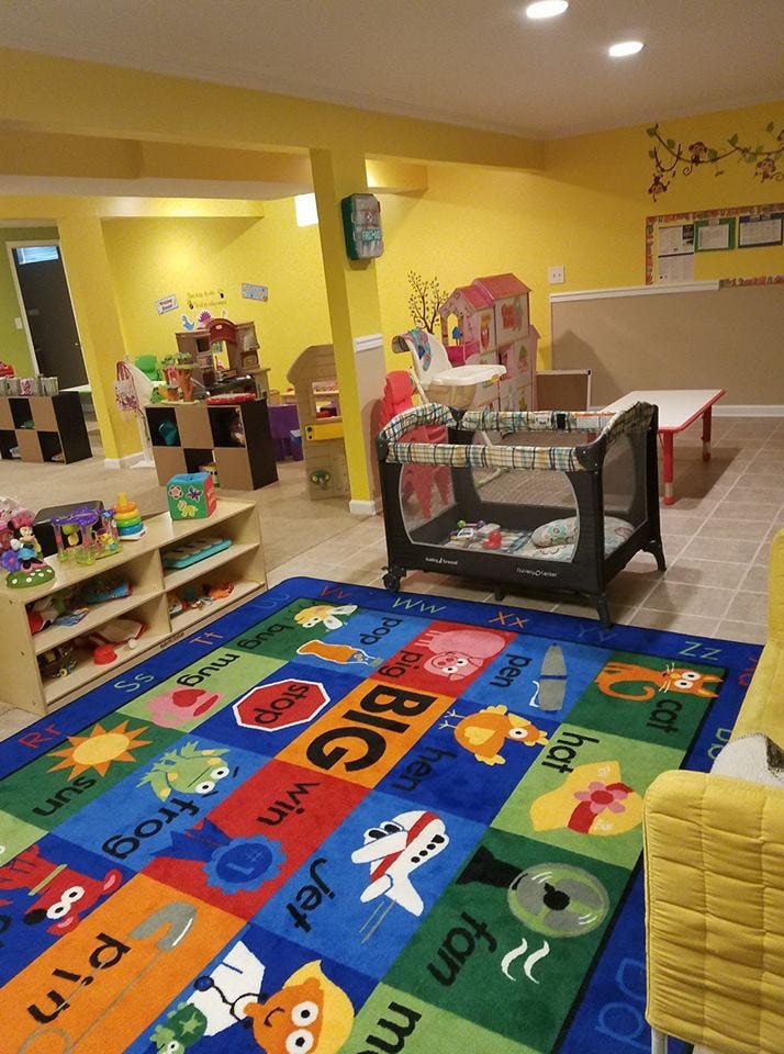 Playroom with a colorful alphabet rug, crib, and shelves of toys