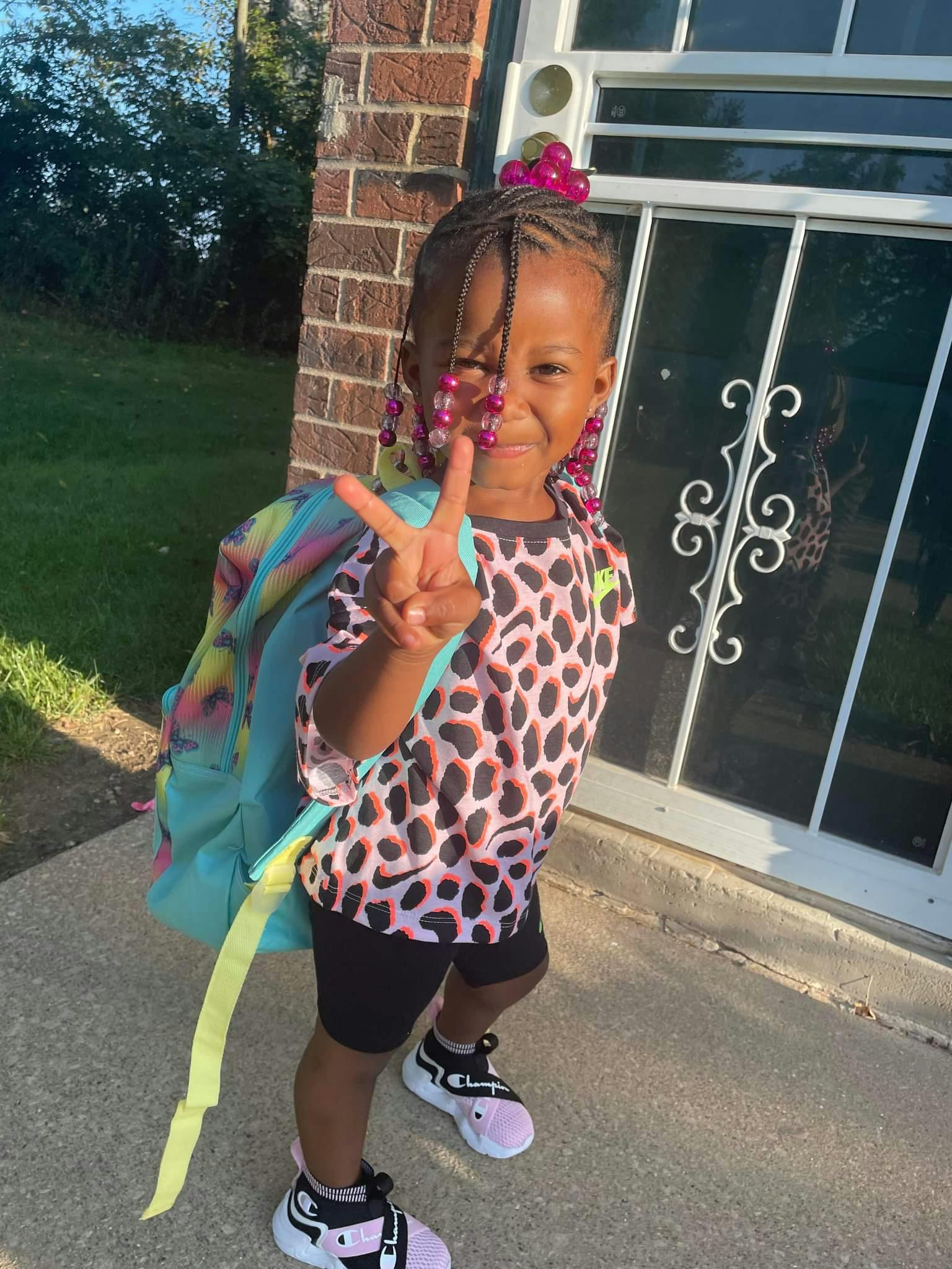 Child wearing a backpack and making a peace sign