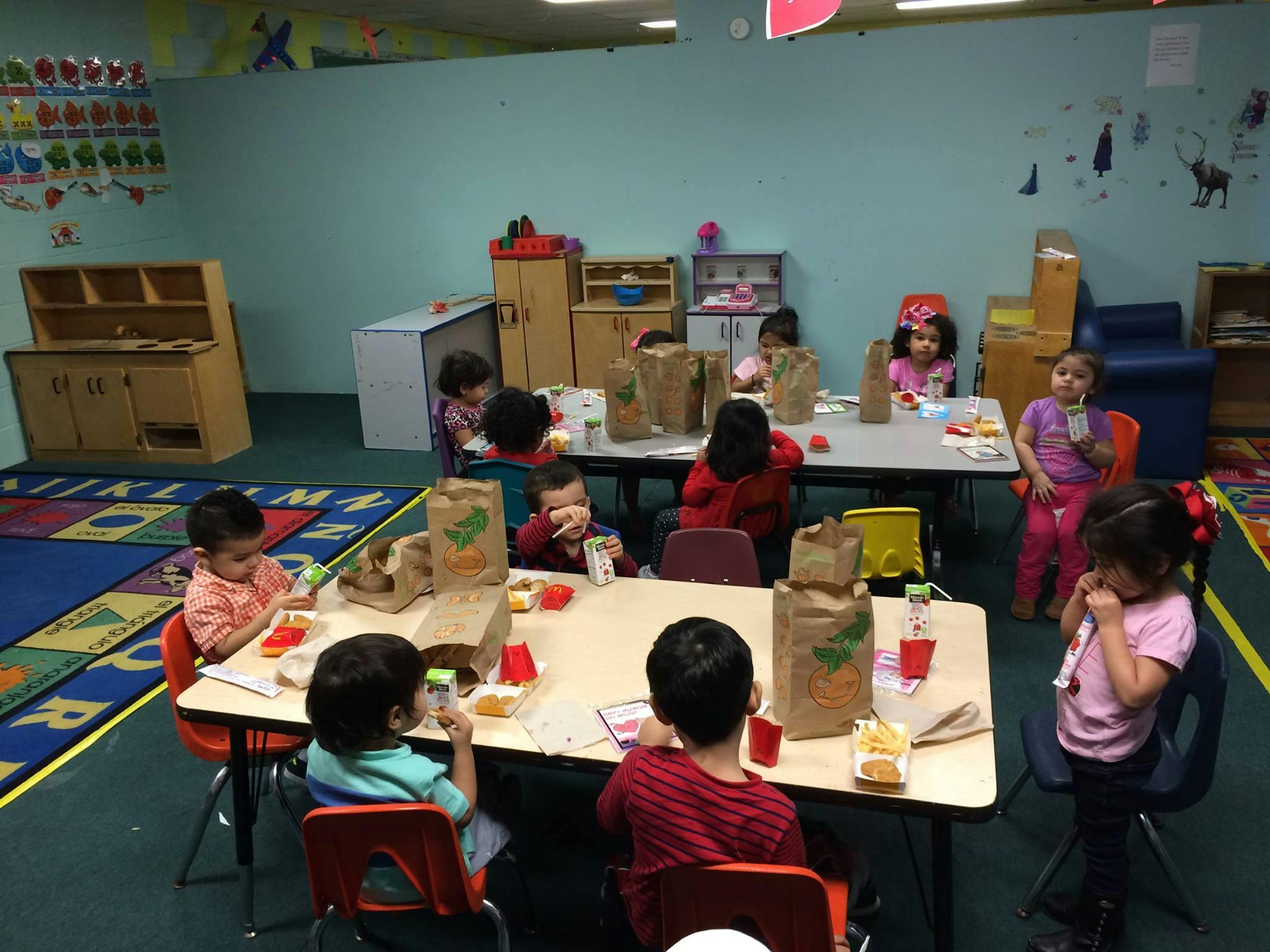 Children sitting at tables in a classroom with brown paper bags