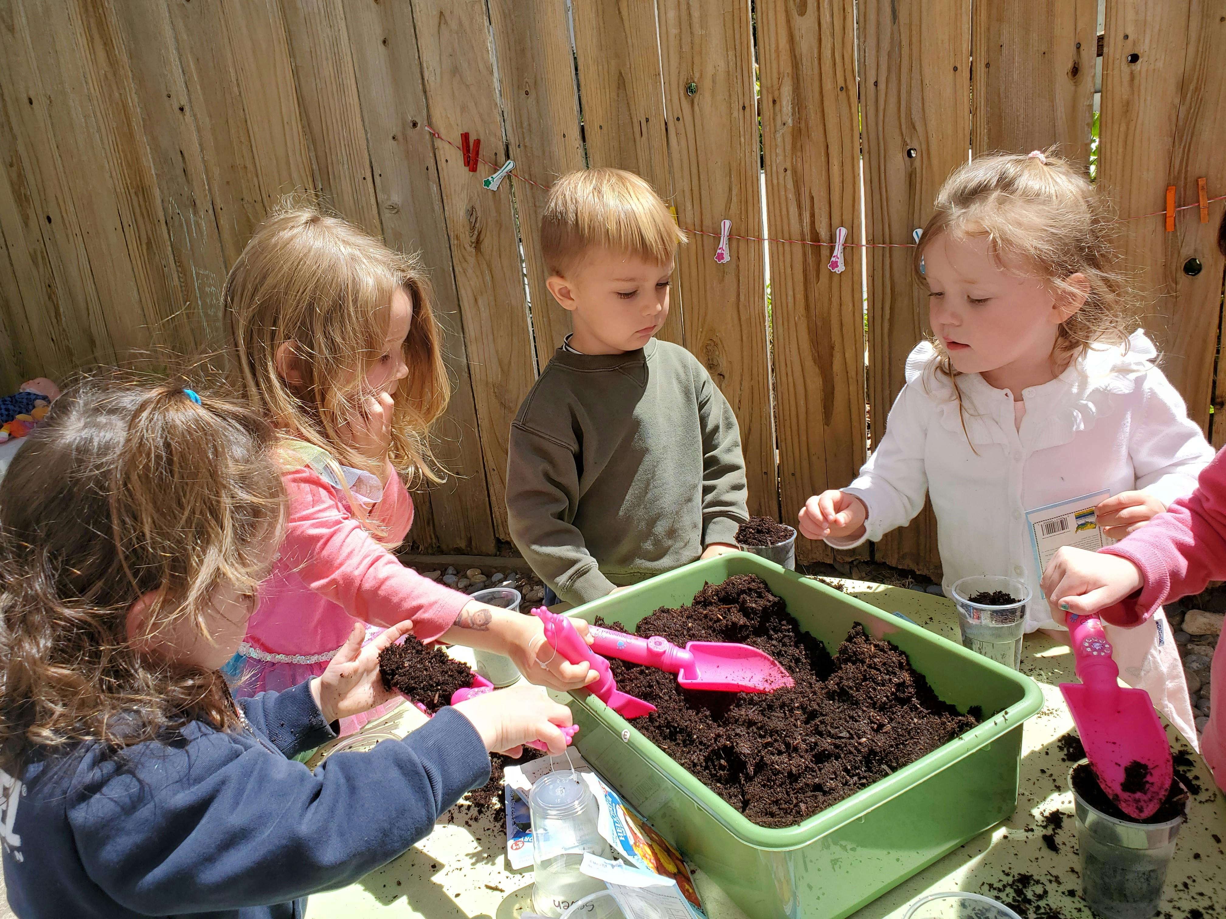 Children playing with soil in a green container