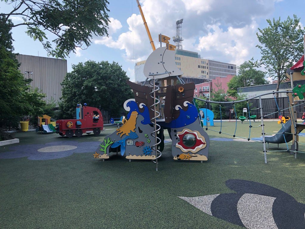 A colorful playground with a pirate ship structure and a red train-shaped play set