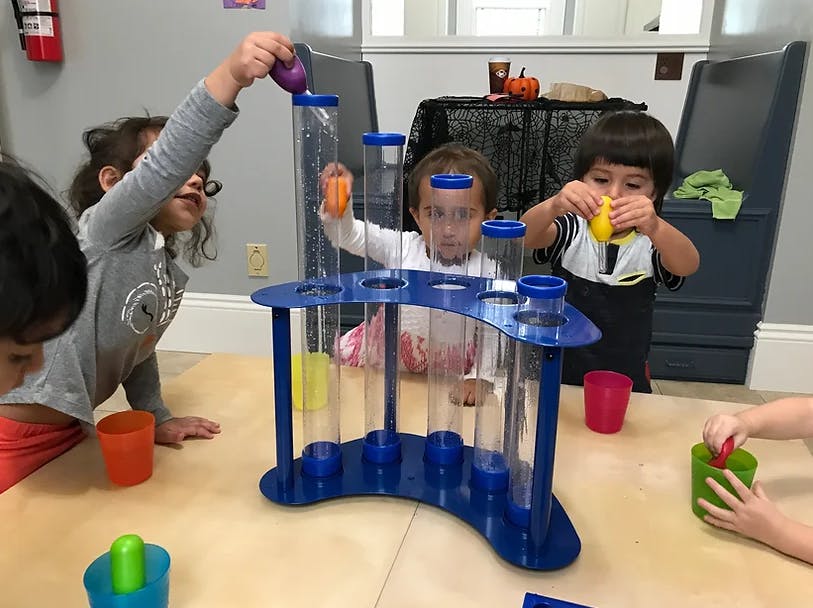 Children playing with a water activity toy with clear tubes