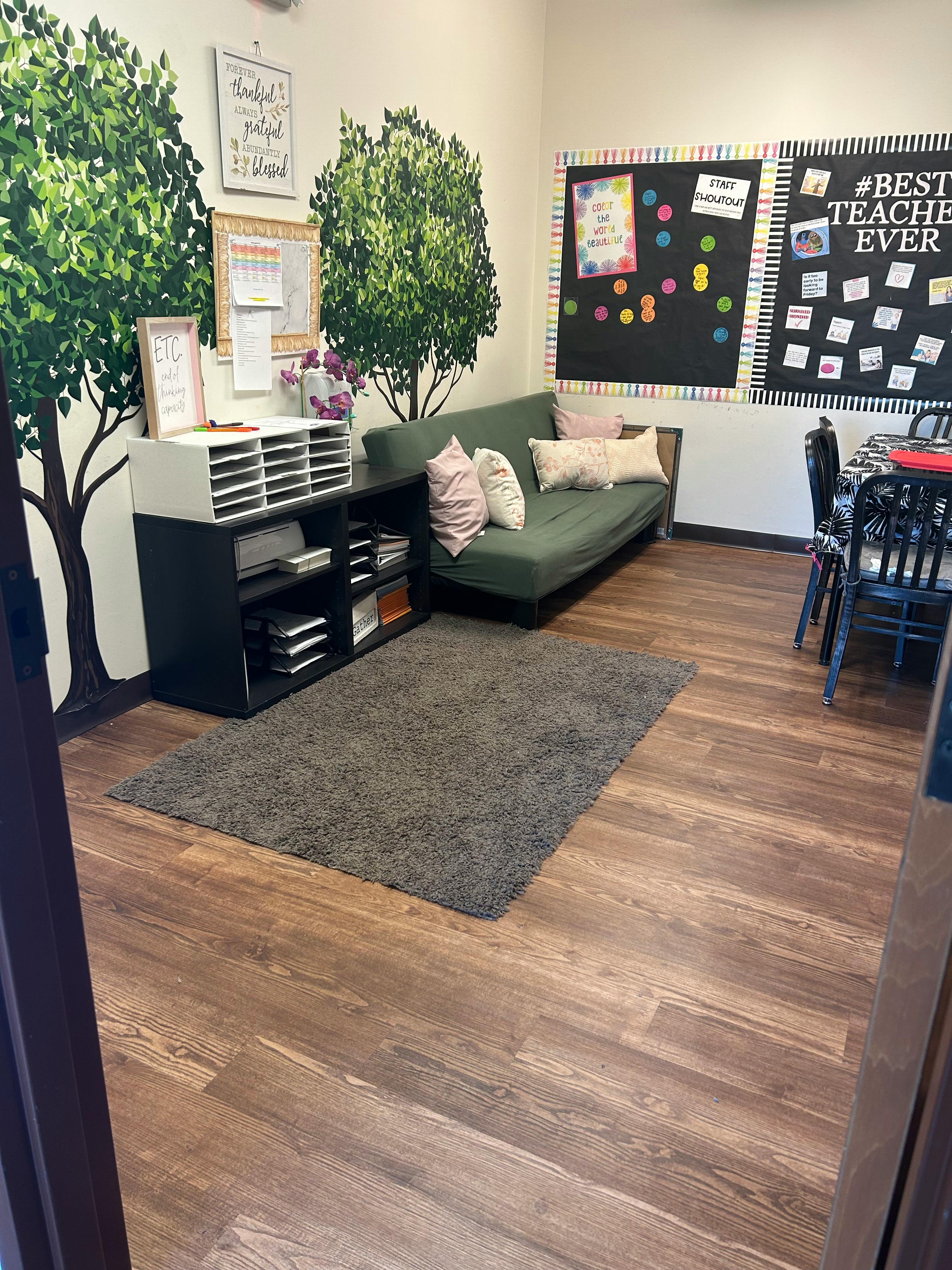 Classroom with tree murals, green sofa, and bulletin boards