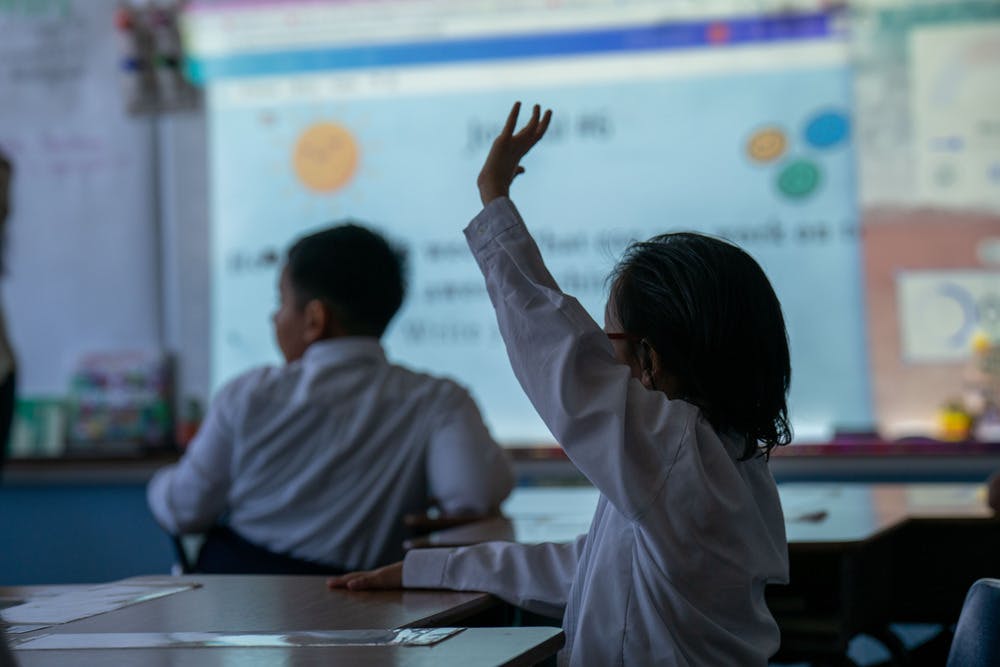 Child raising a hand in a classroom