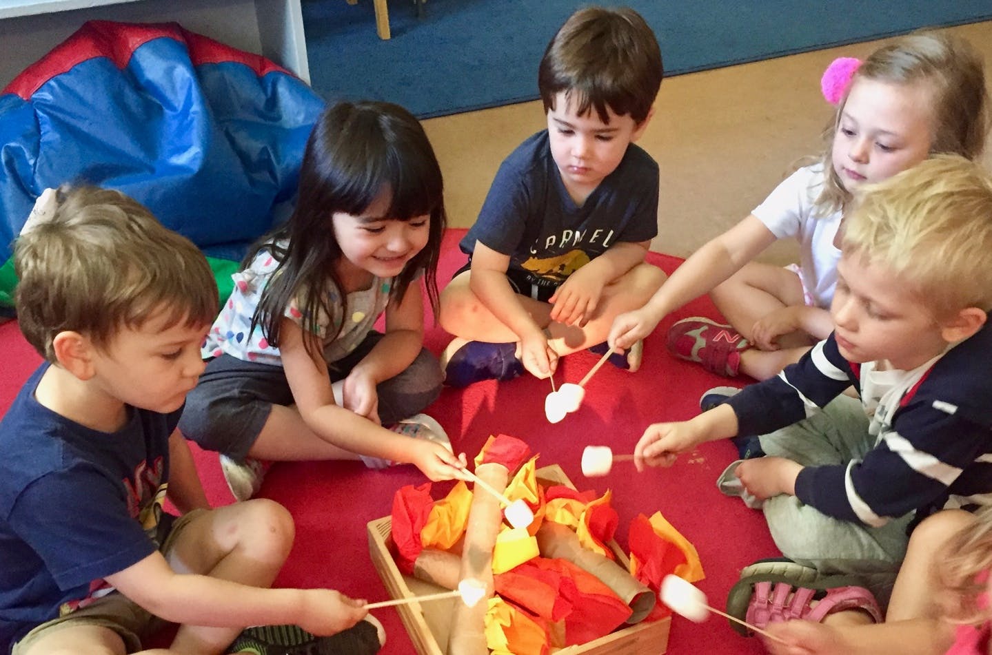 Children sitting around a pretend campfire with marshmallows on sticks