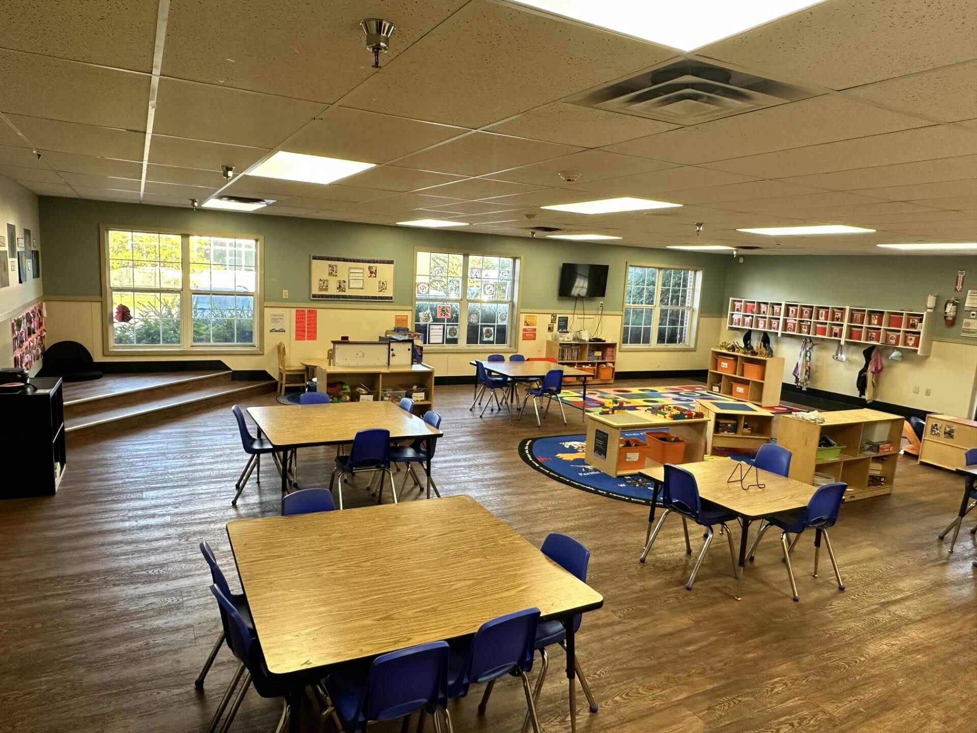 Empty classroom with small tables, chairs, and play areas