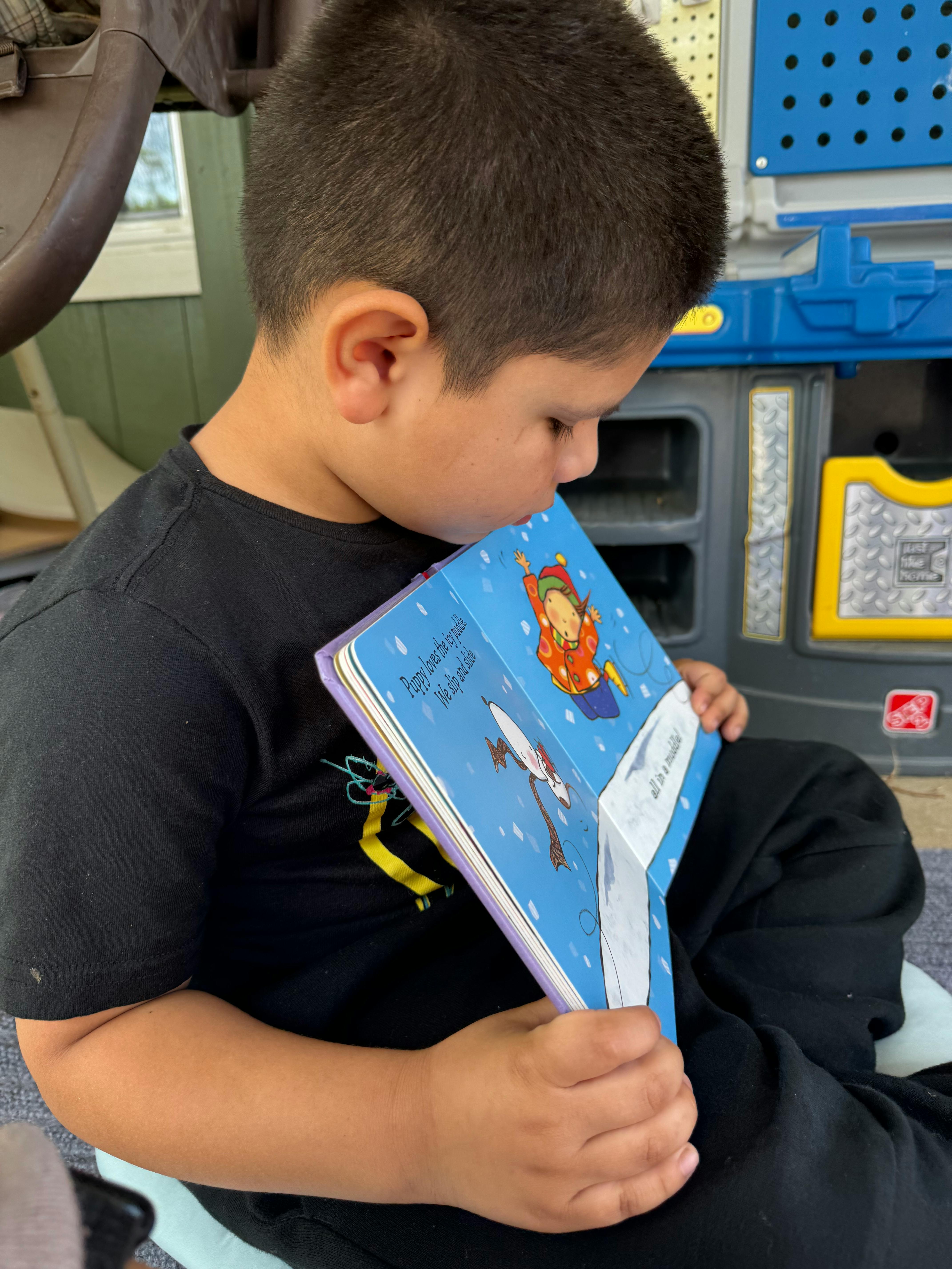 Child looking down at an open book with illustrations