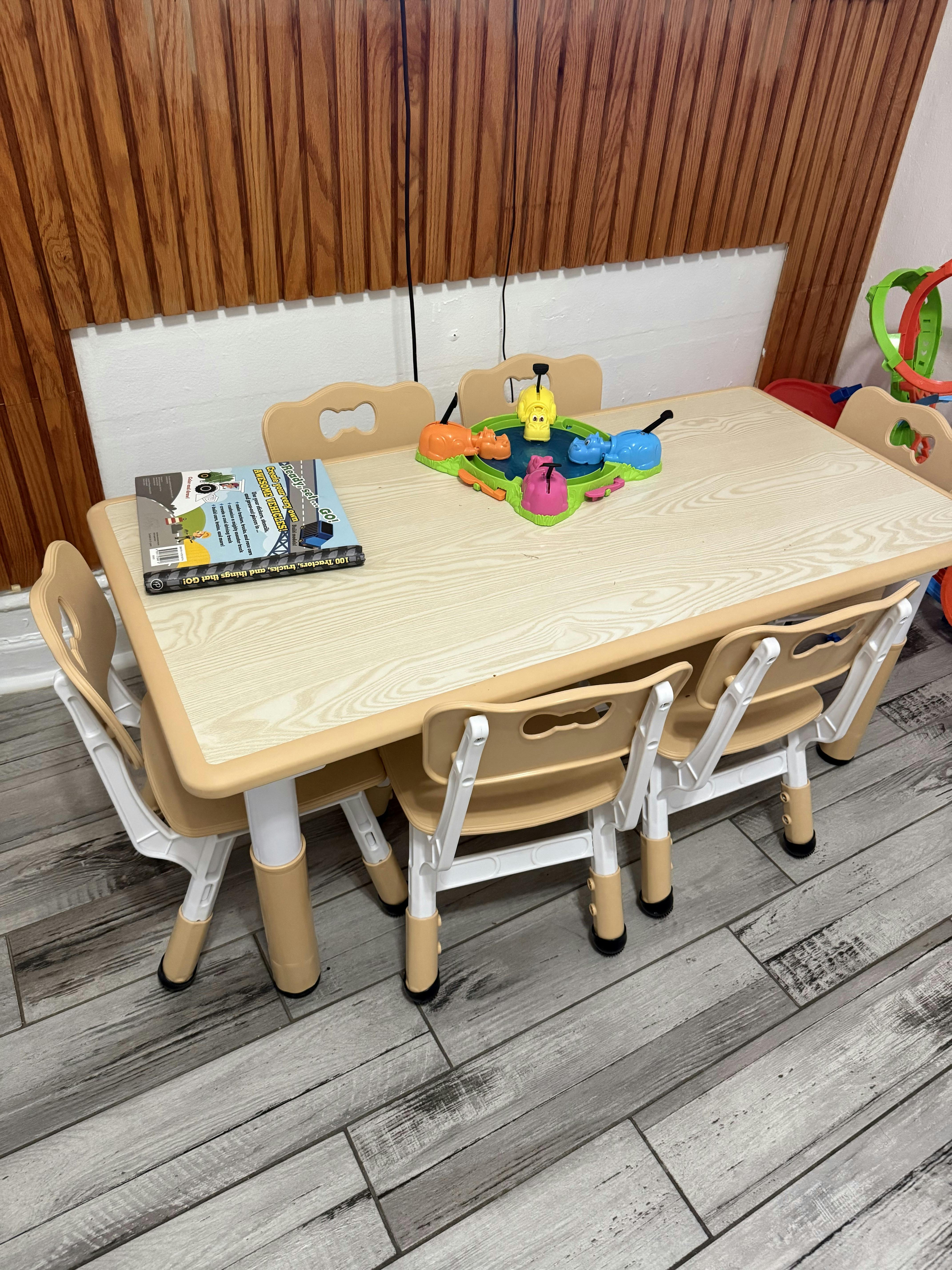 A children's table with four chairs, a Hungry Hungry Hippos game, and a book