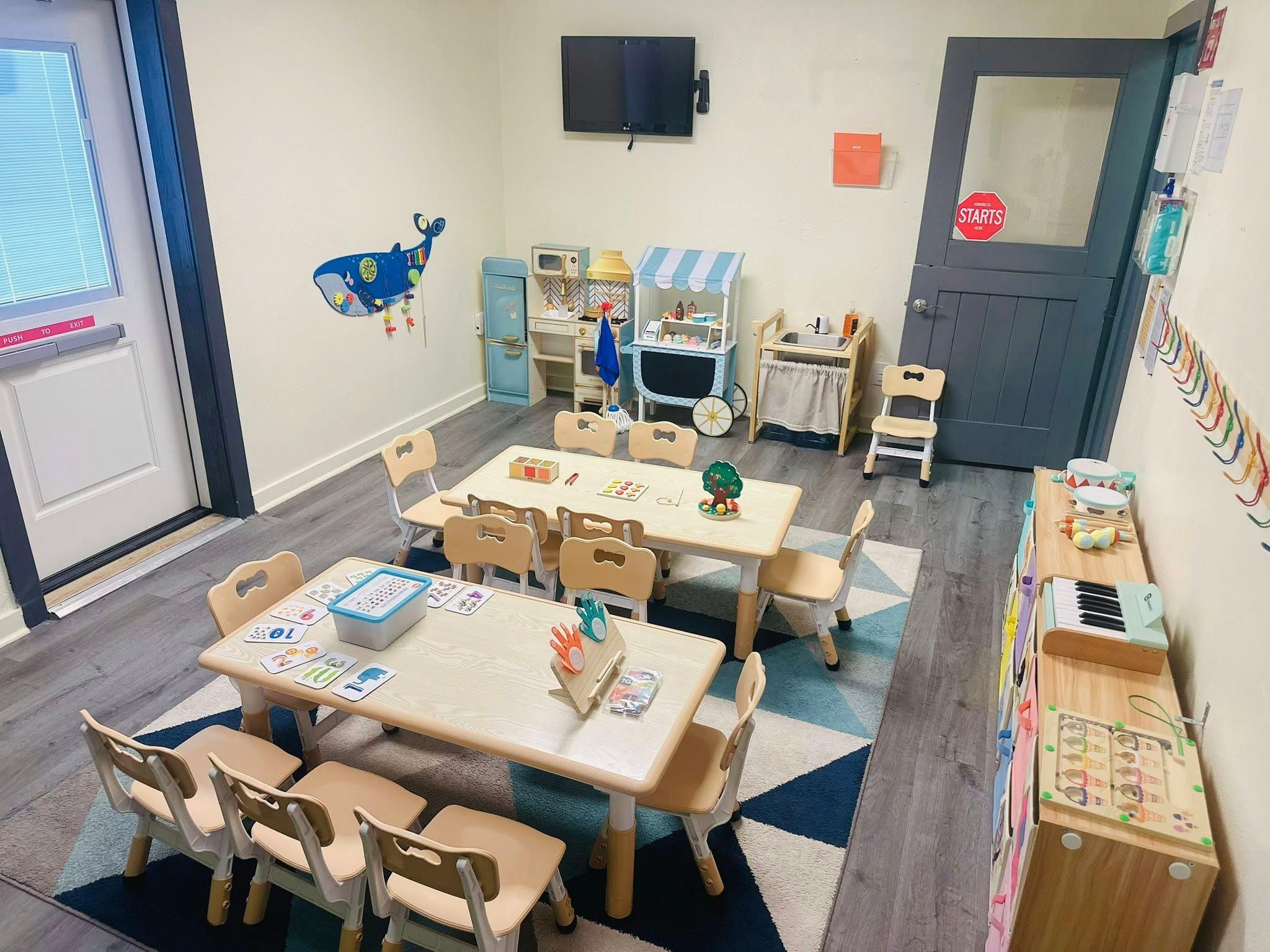 Classroom with small tables and chairs, toys, and a whale decal on the wall