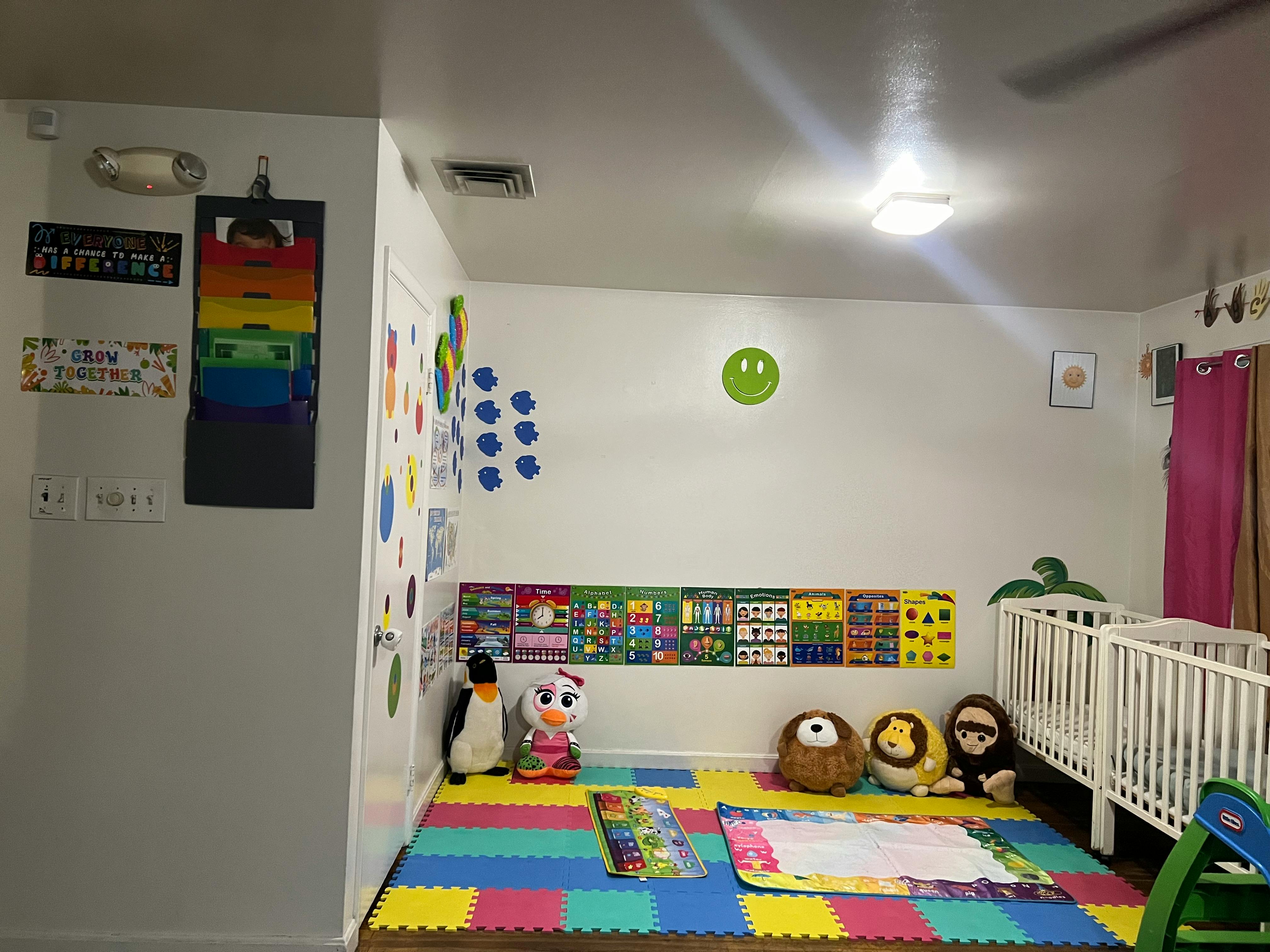 Playroom with colorful floor mats, stuffed animals, and a crib