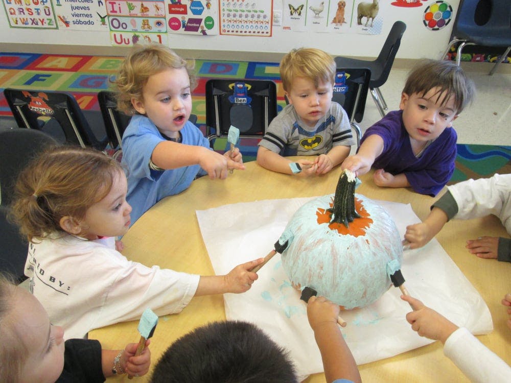 Children painting a pumpkin in a classroom