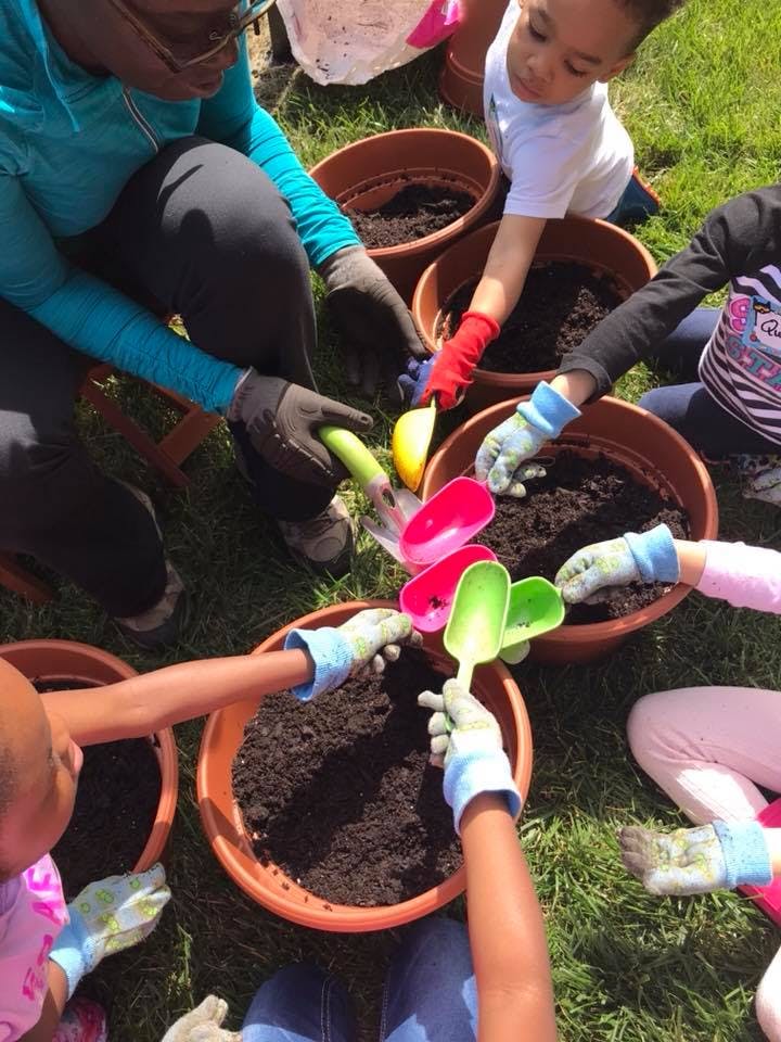 People and children in gloves planting in pots