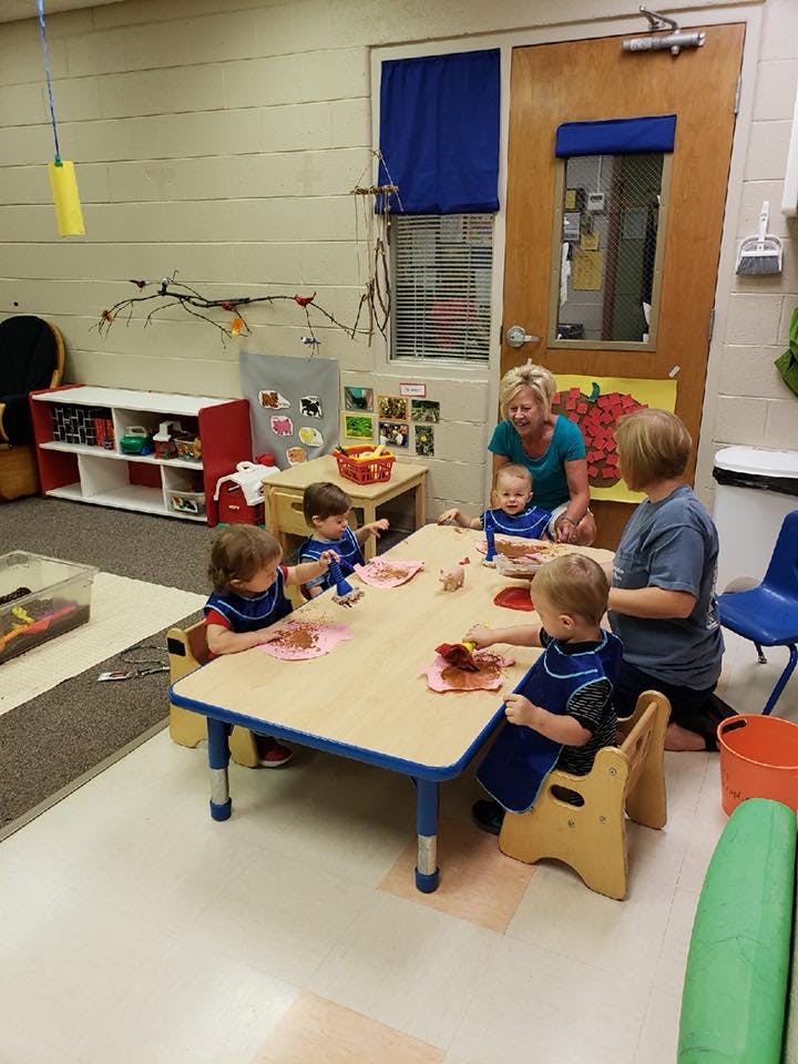 Adults and children at a table in a classroom