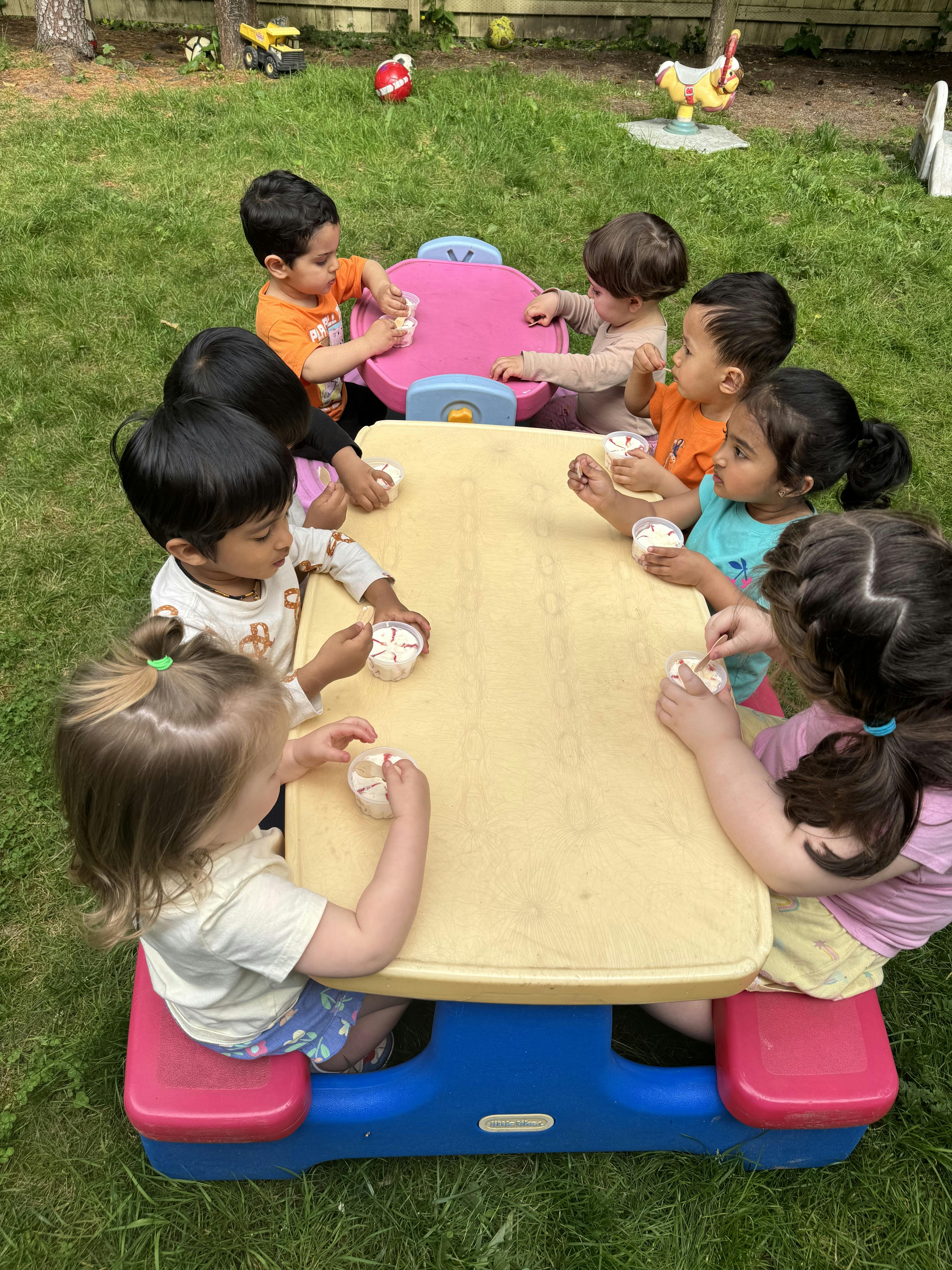 Children sitting around a small table outdoors