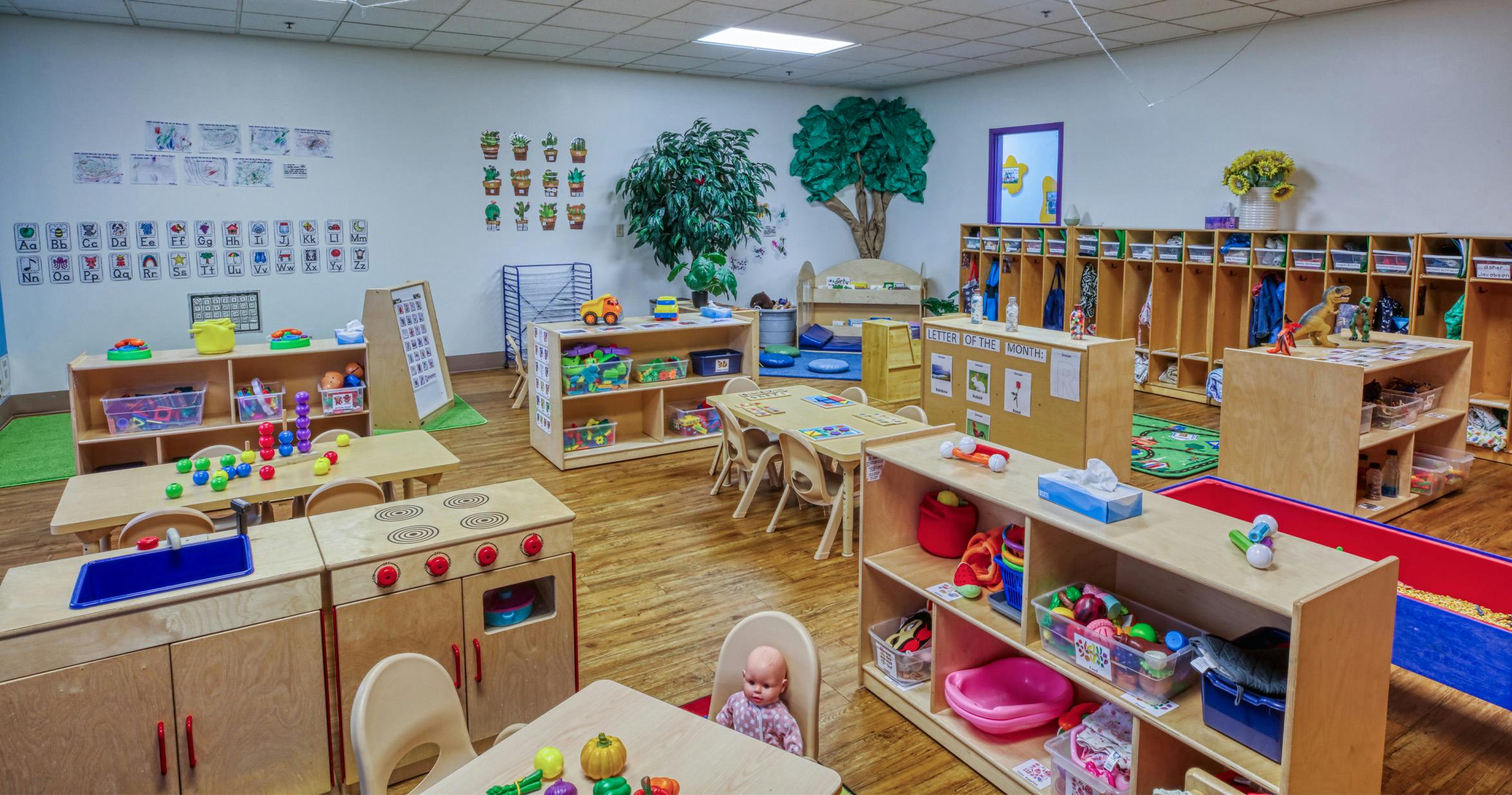 An empty early childhood classroom with multiple play areas and cubbies