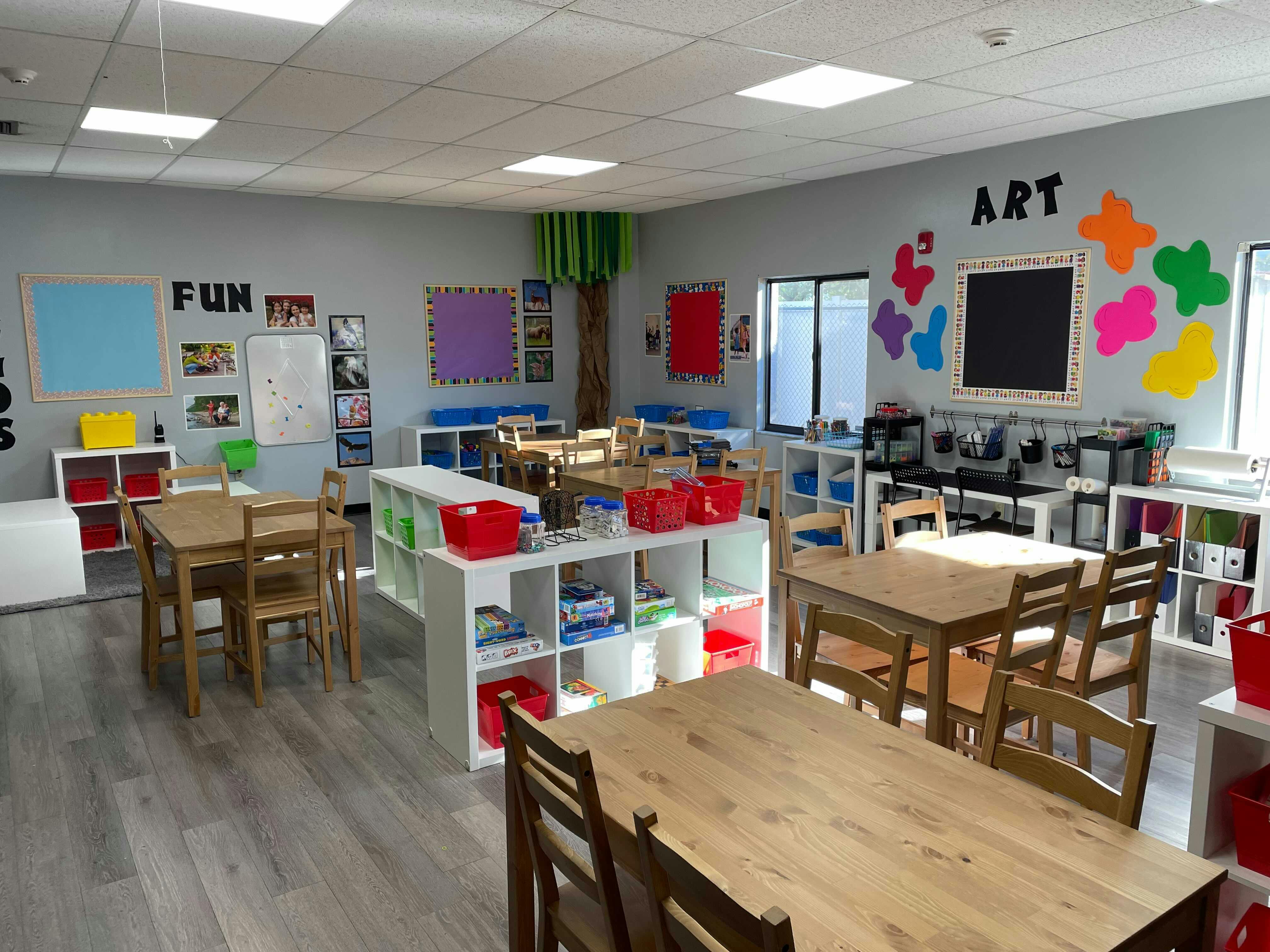 Classroom with tables, chairs, and shelves with art supplies