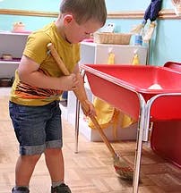 Child sweeping the floor with a broom