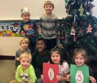 Seven children posing in front of a decorated Christmas tree