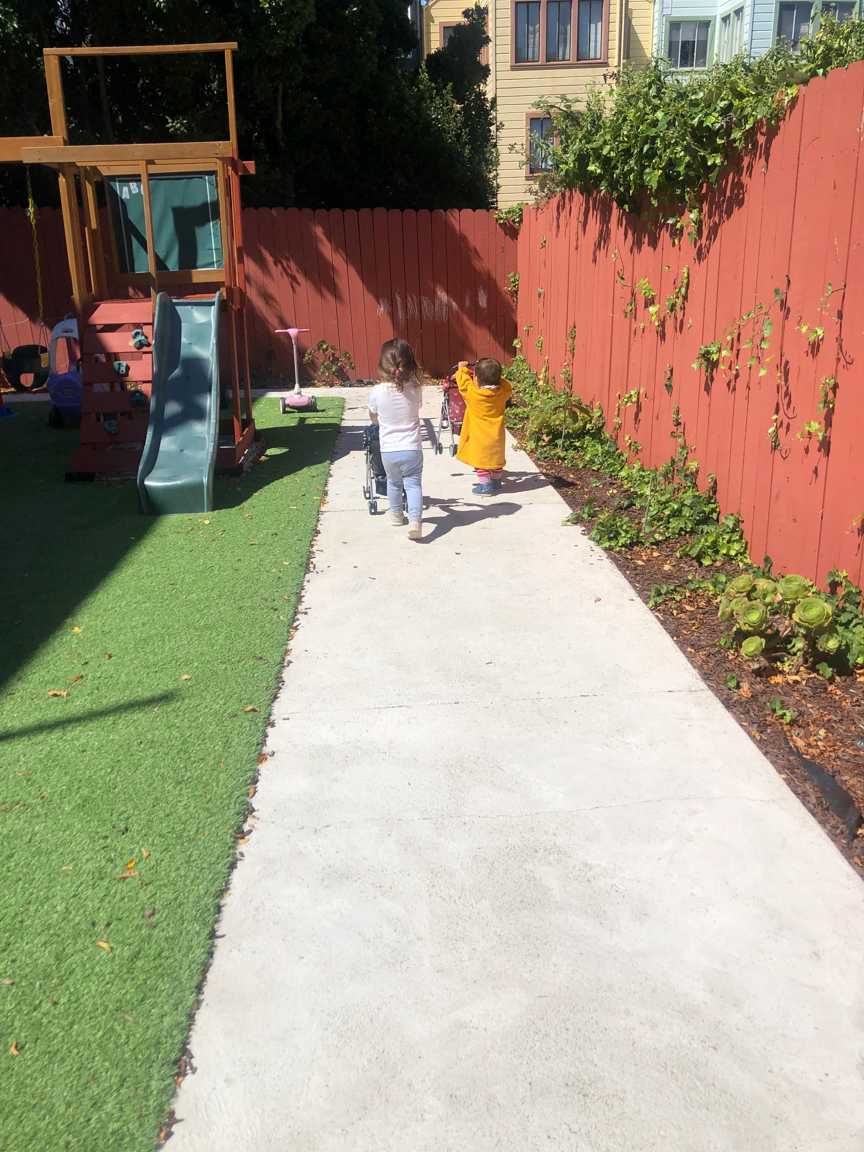 Two children walking on a path next to a playground