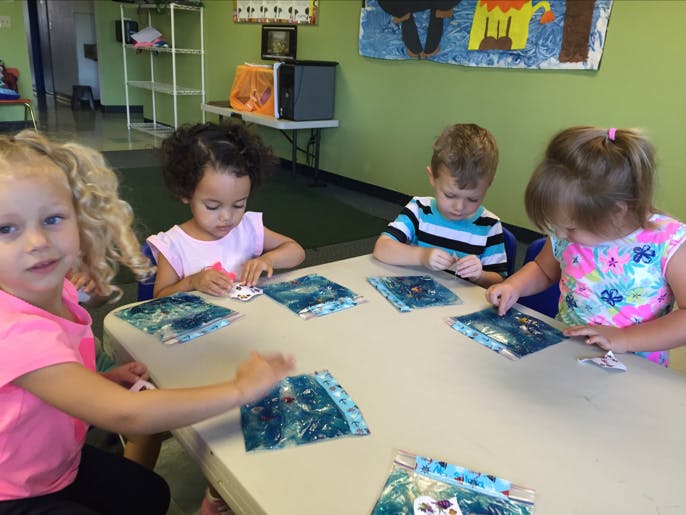 Four children sitting at a table doing an activity
