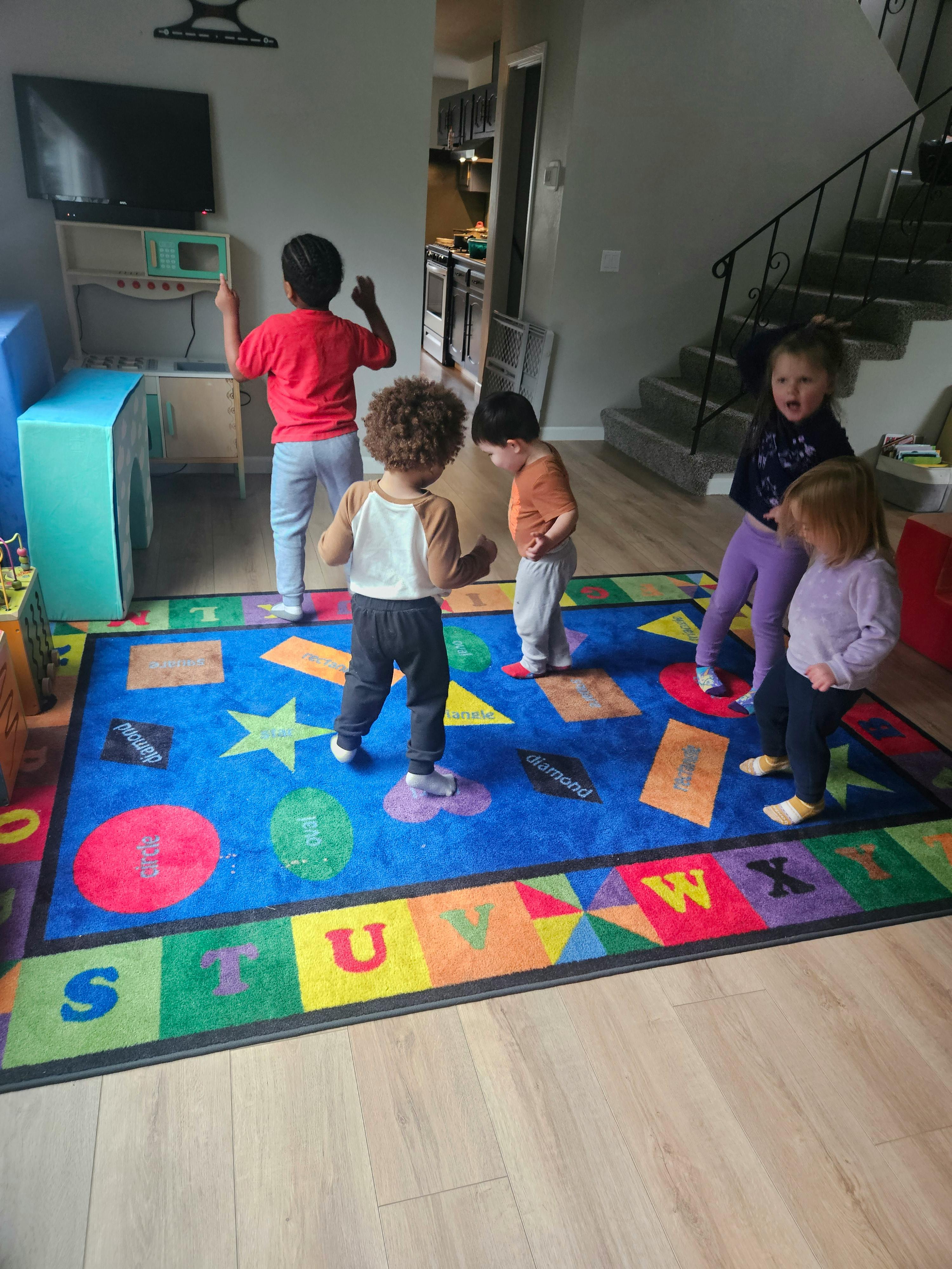 Group of children playing on a colorful alphabet and shape area rug