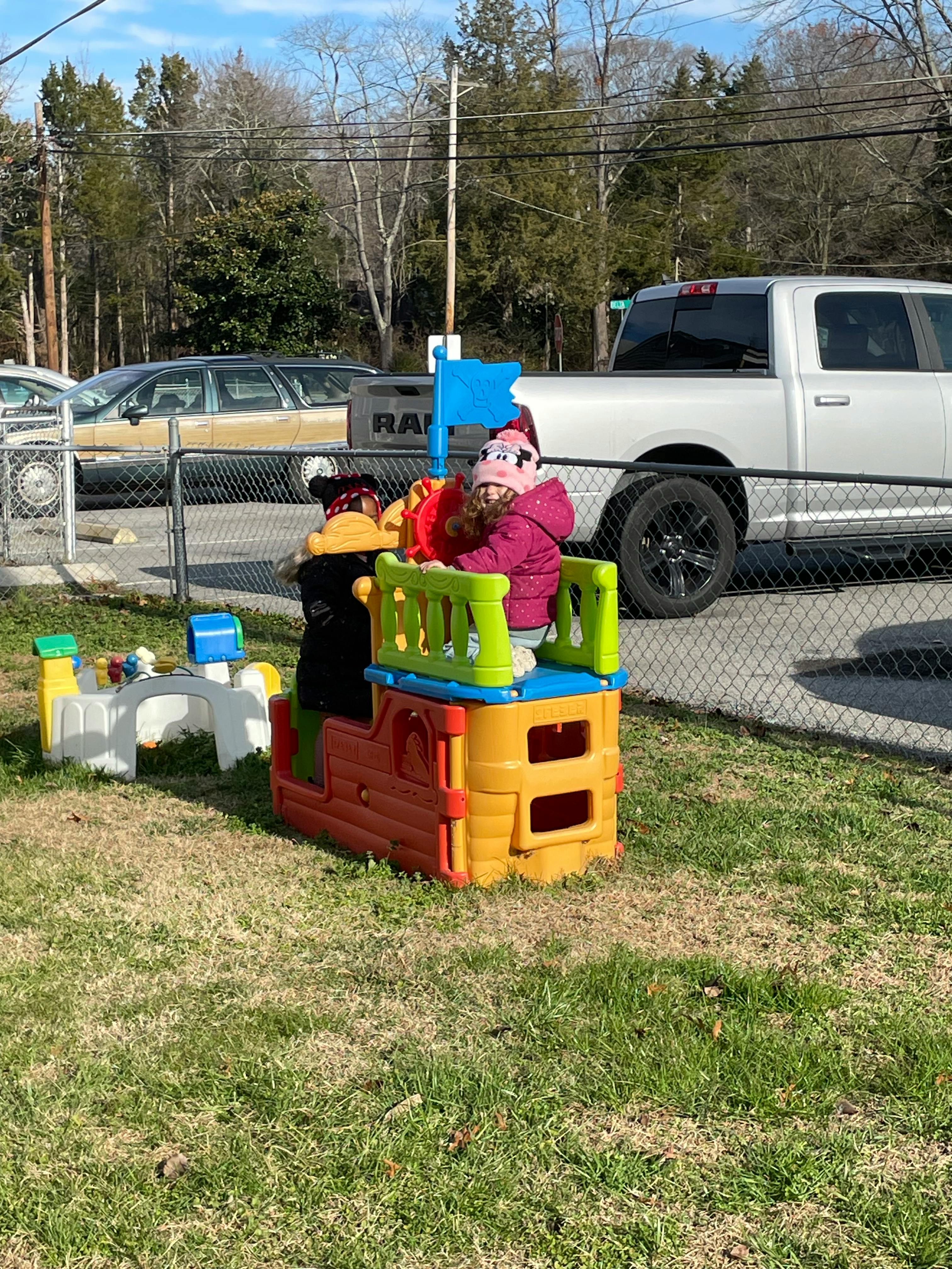 Child in a pink coat playing on a colorful plastic play structure