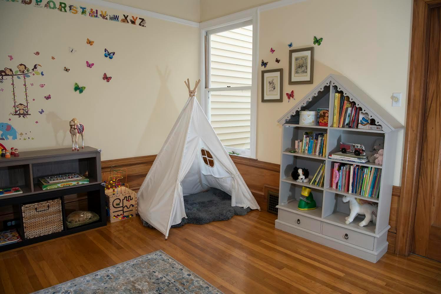 Playroom with a white teepee, a house-shaped bookshelf, and a storage unit