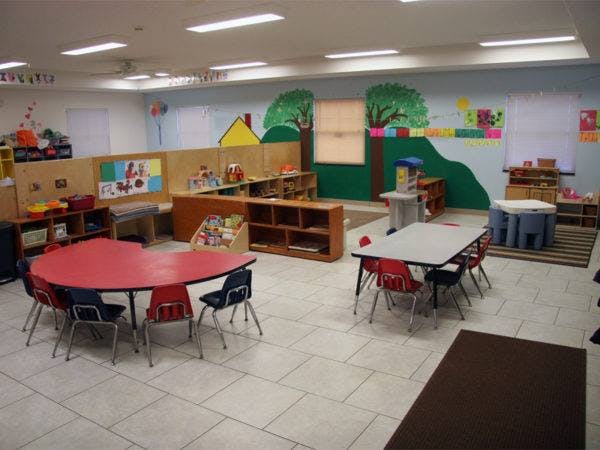 Empty classroom with small tables and chairs, colorful wall murals