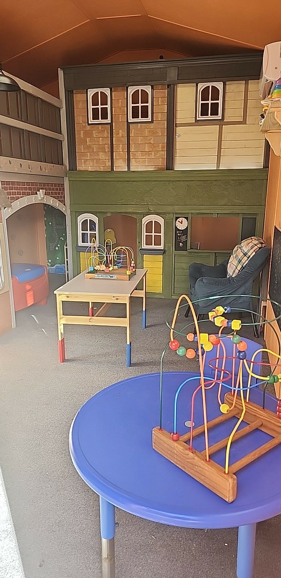 Playroom with bead maze toys on tables and a playhouse structure