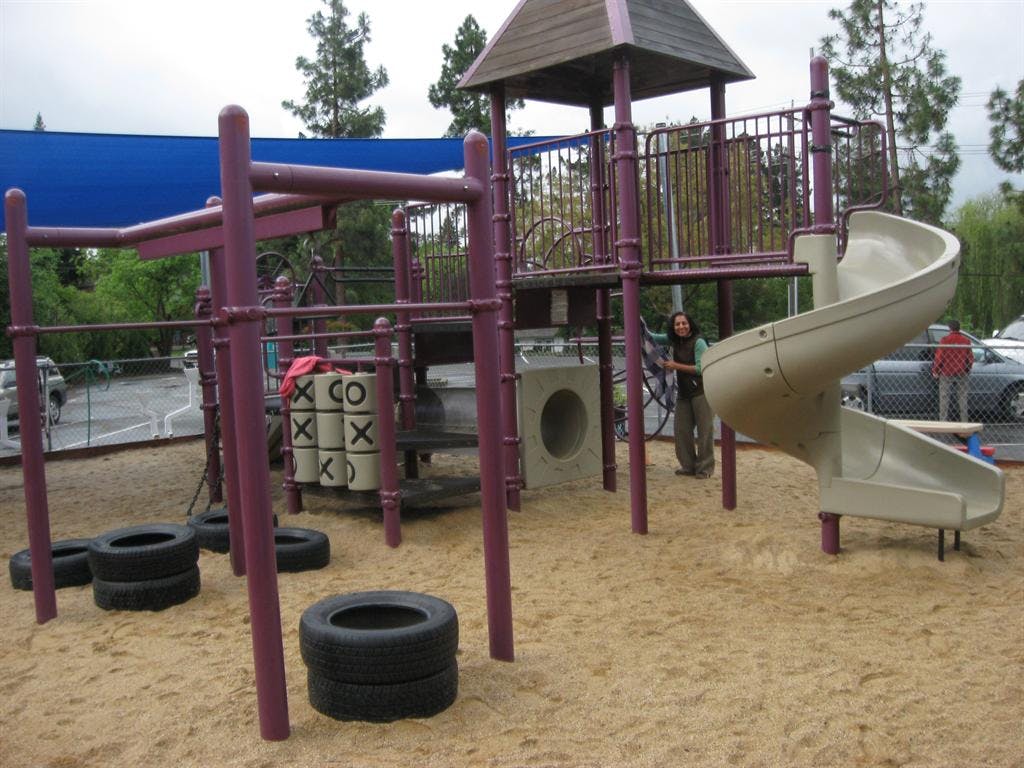 Playground with purple climbing structure, spiral slide, and tic-tac-toe game