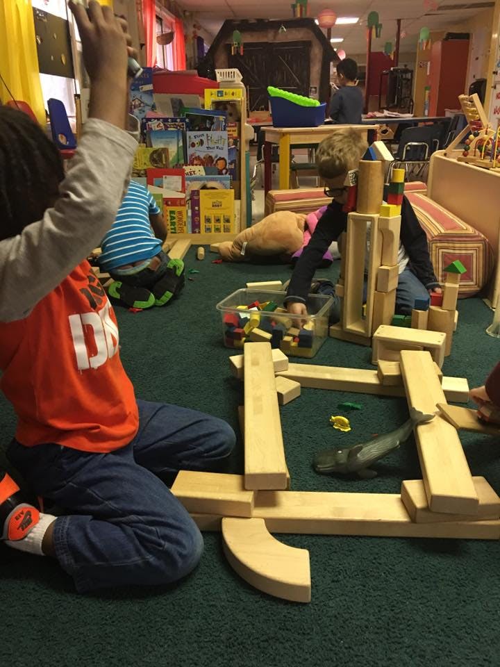 Children playing with wooden blocks on a green carpet
