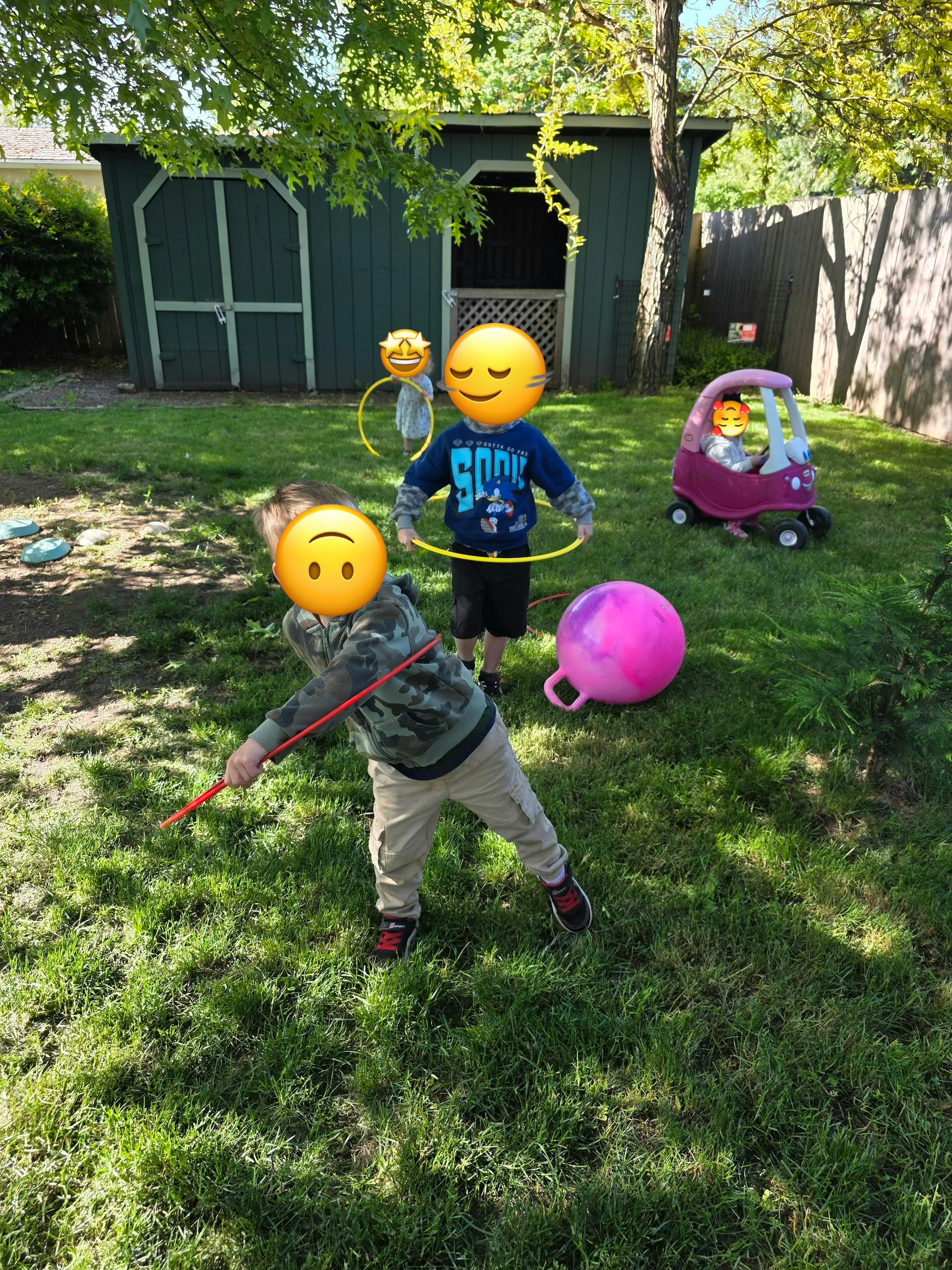 Children playing with hula hoops and toys in a grassy backyard