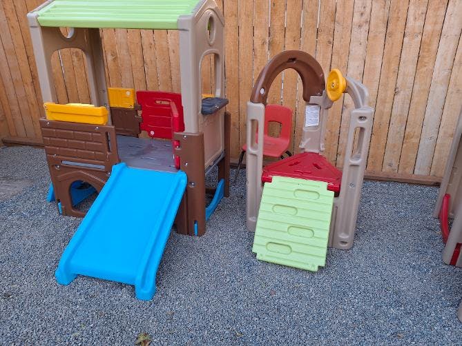 Plastic playground playsets with slides on a gravel surface