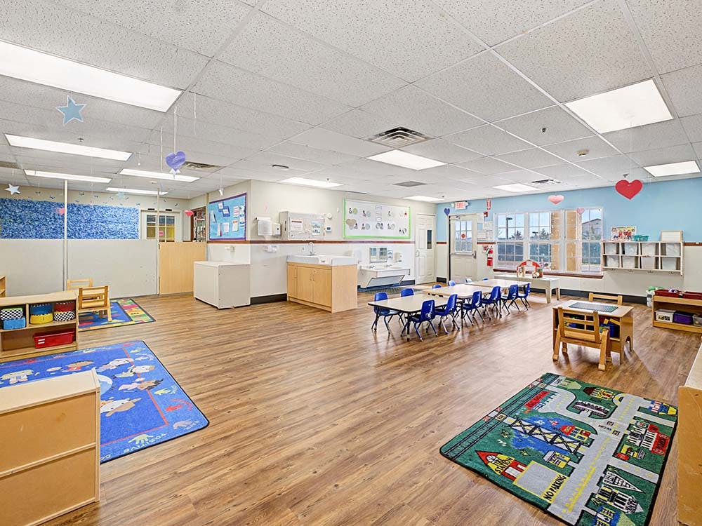 A colorful and spacious daycare classroom with small tables and chairs
