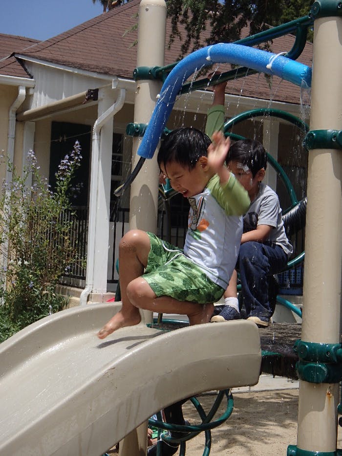 Child on a playground slide with water spraying