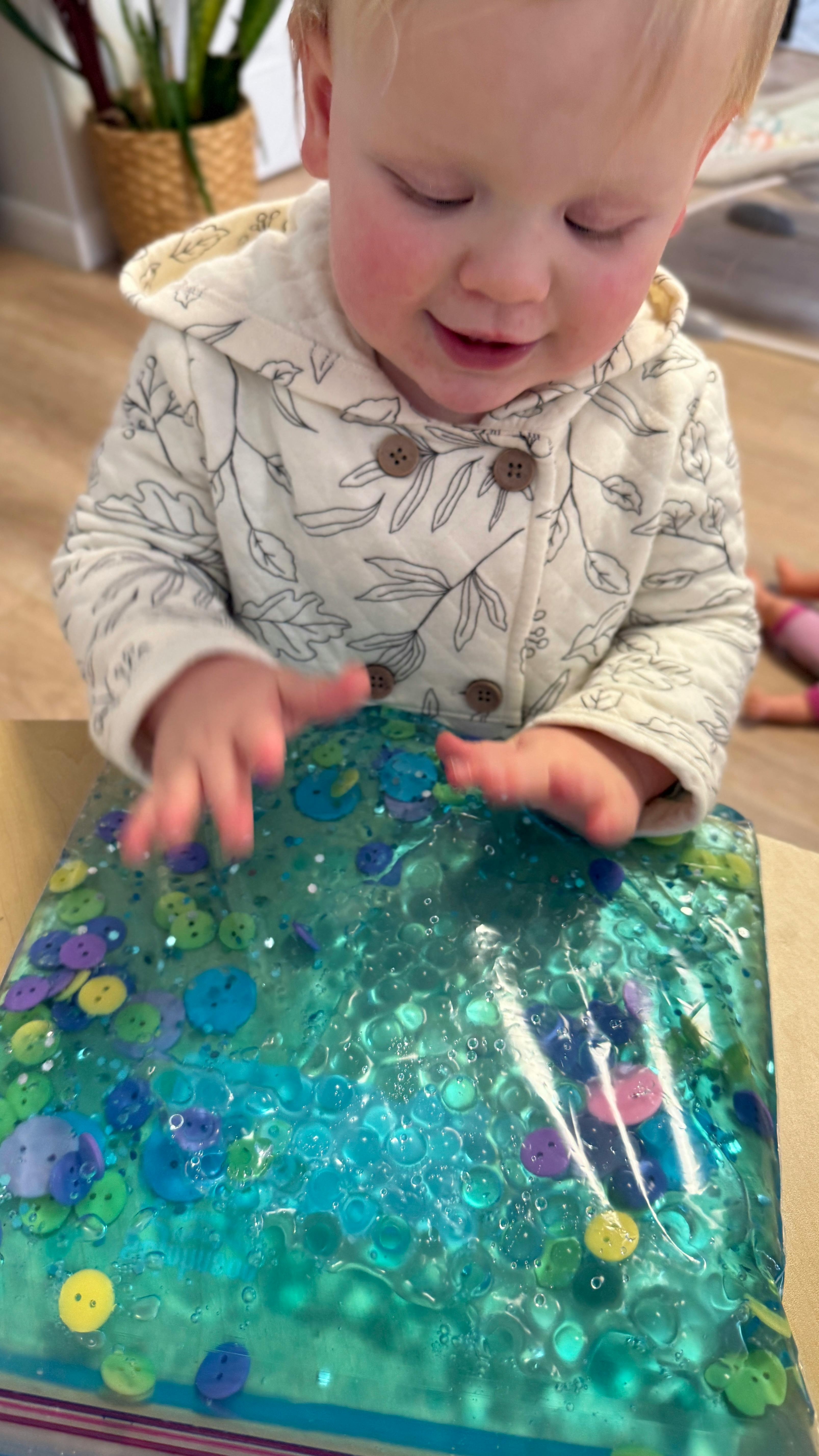 Child playing with a sensory bag filled with gel and buttons