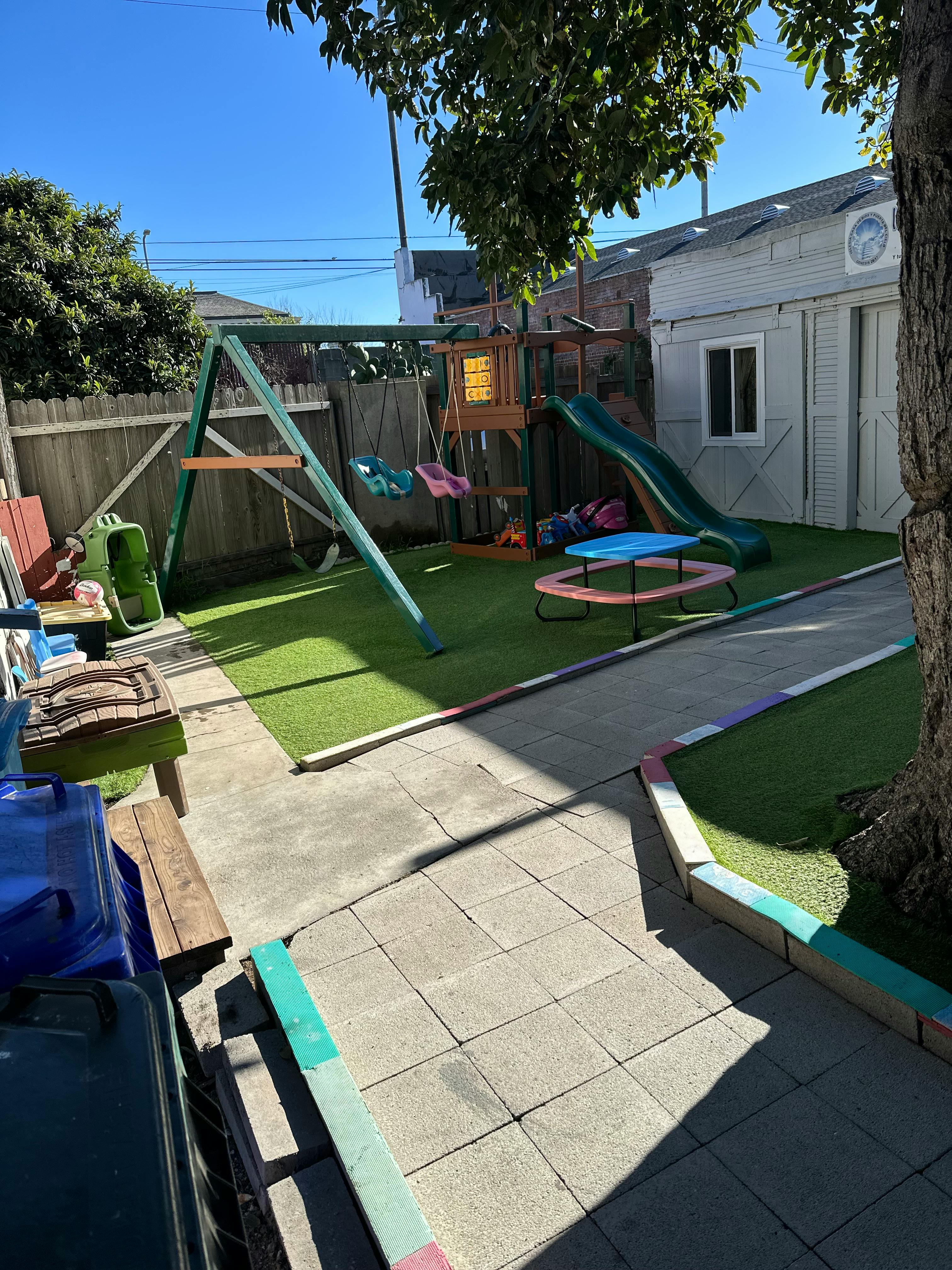 Playground set on artificial turf next to a paved walkway