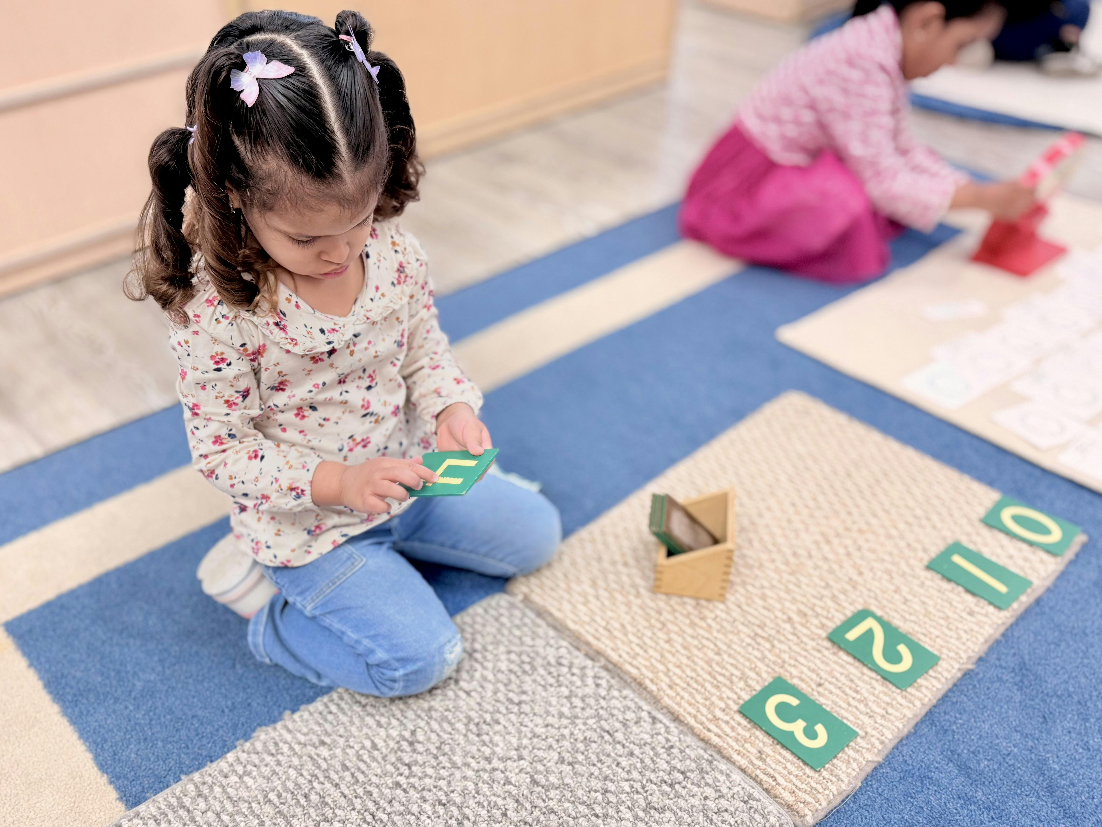 Child on floor holding a green number block