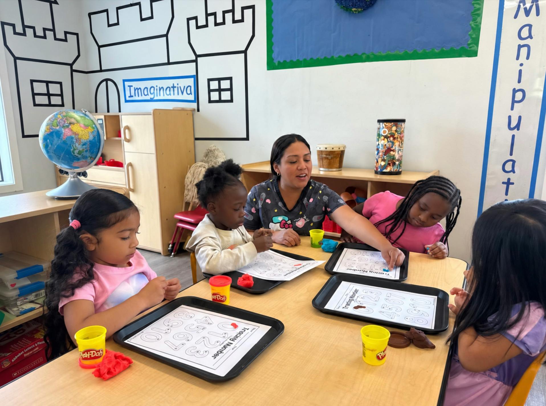 Teacher and children at a table working on number tracing activities