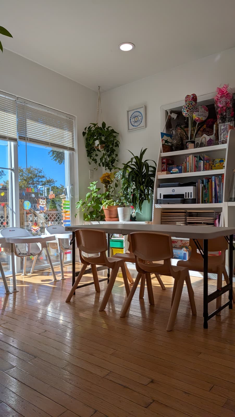 Classroom with tables and chairs, plants, and a bookshelf