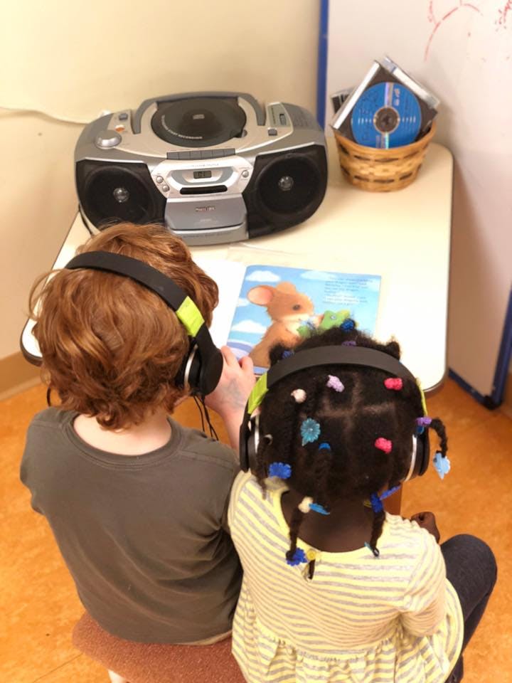 Two children wearing headphones listening to a boombox